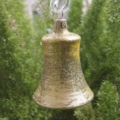 A closeup shot of a glittery gold bell hanging on a stand